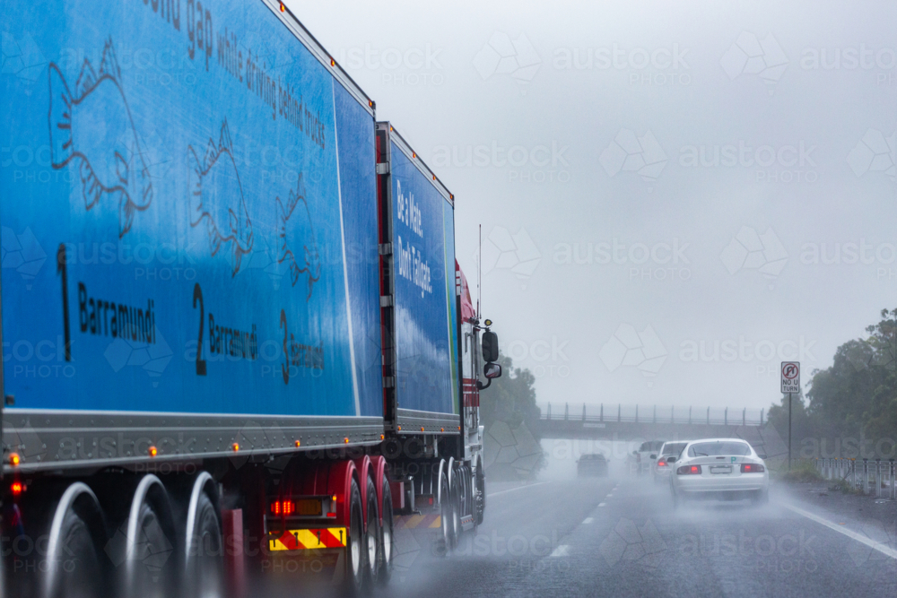 Truck and cars traveling down slippery highway road on wet rainy day - Australian Stock Image