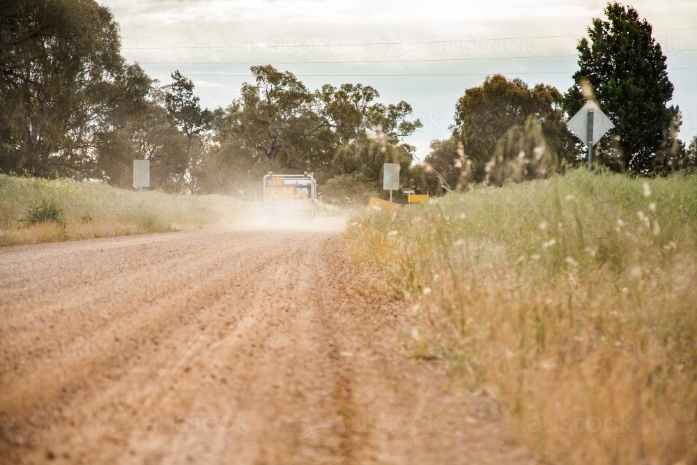 Truck driving down dirt road with dust cloud behind - Australian Stock Image