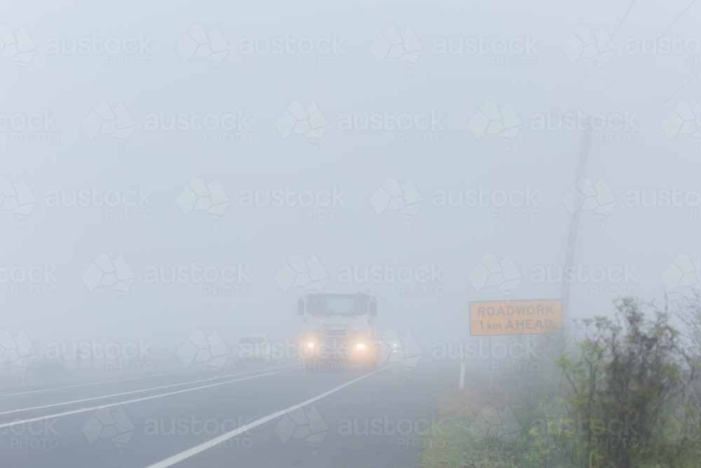 truck travelling on highway road through fog with low visibility - Australian Stock Image