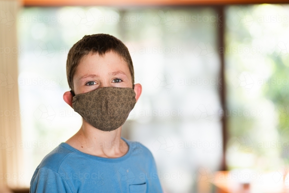 Tween boy inside during covid wearing a re-usable face mask - Australian Stock Image