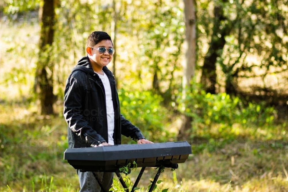 Tween boy outside playing keyboard - Australian Stock Image