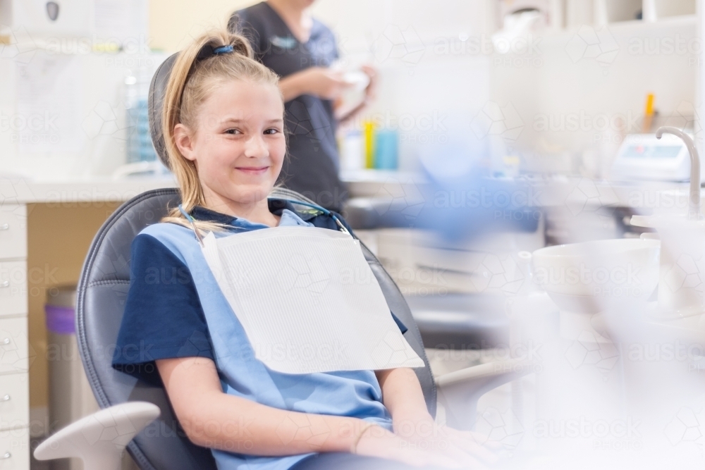 Tween girl at the dentist sitting in chair - Australian Stock Image