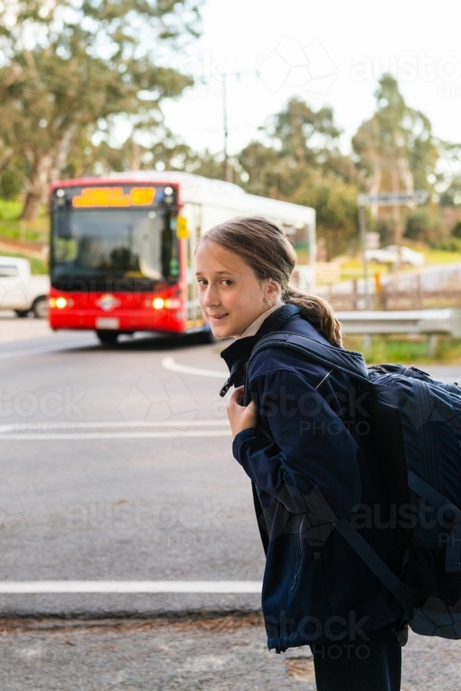 tween girl catching the bus to school, smiling to camera - Australian Stock Image