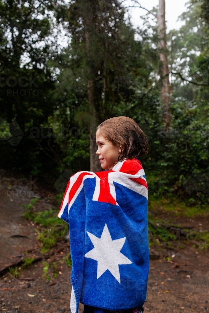 Tween girl in Australian flag towel in bushland by waterhole - Australian Stock Image