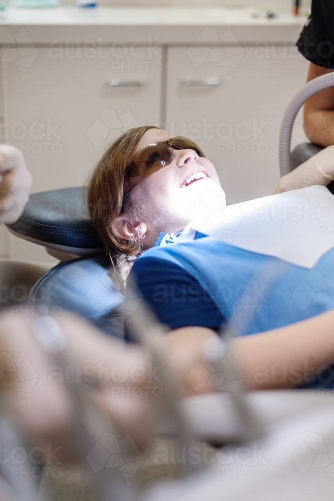 Tween girl lying in a chair smiling at the dentist - Australian Stock Image