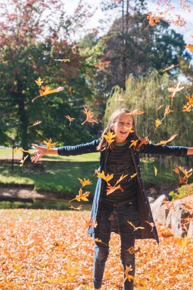 tween girl throwing autumn leaves - Australian Stock Image