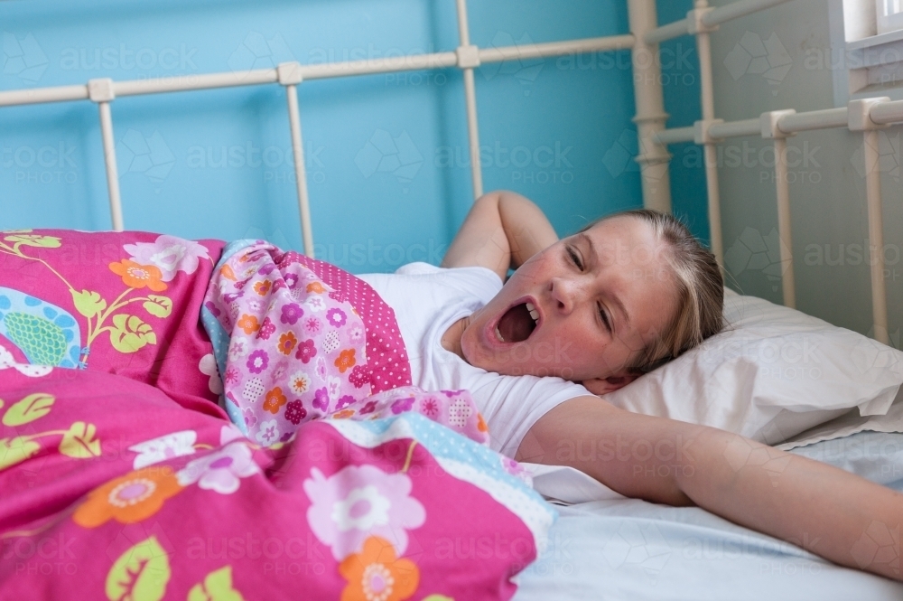 Tween girl waking up with a big yawn - Australian Stock Image