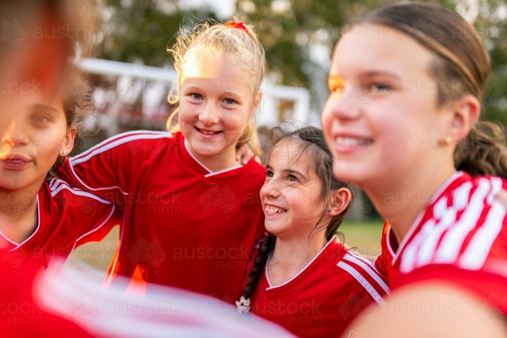 Tween girls football team members in a close pre-game huddle - Australian Stock Image