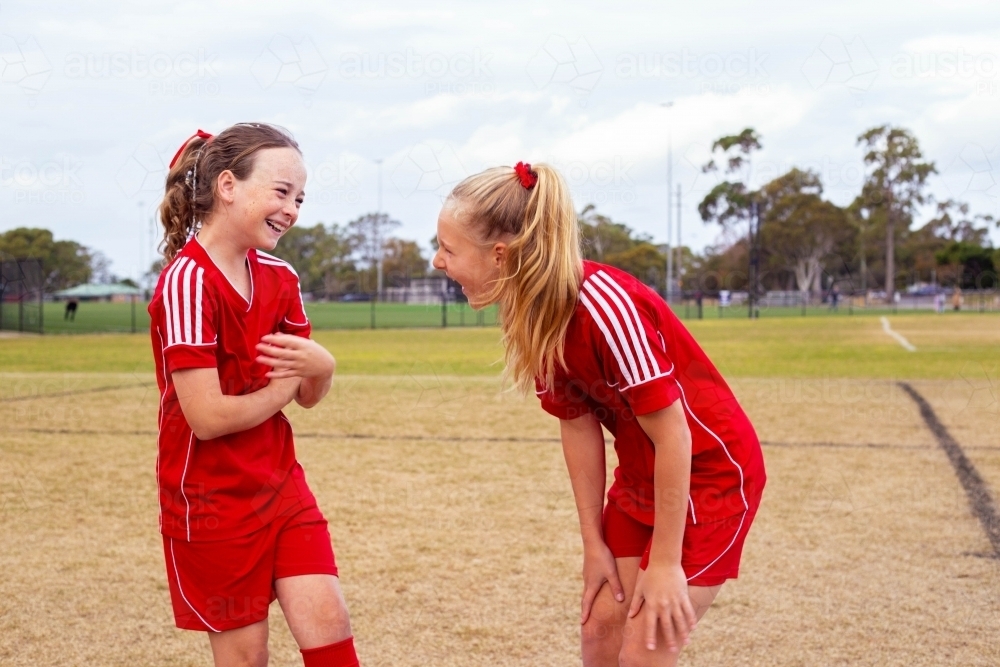 Tween girls from the same football team laughing together - Australian Stock Image