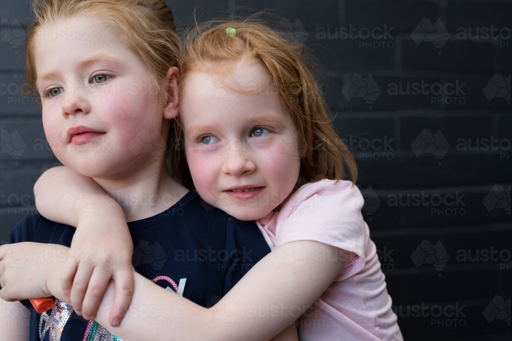 Twin sisters hugging and smiling - Australian Stock Image