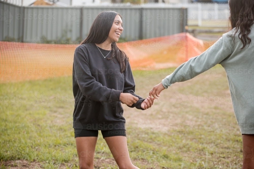 Two Aboriginal teen girls playing together outside - Australian Stock Image