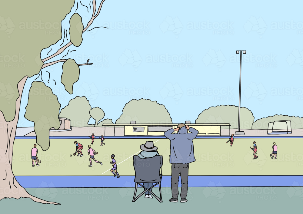 Two adults watching children play winter hockey game from sidelines - Australian Stock Image