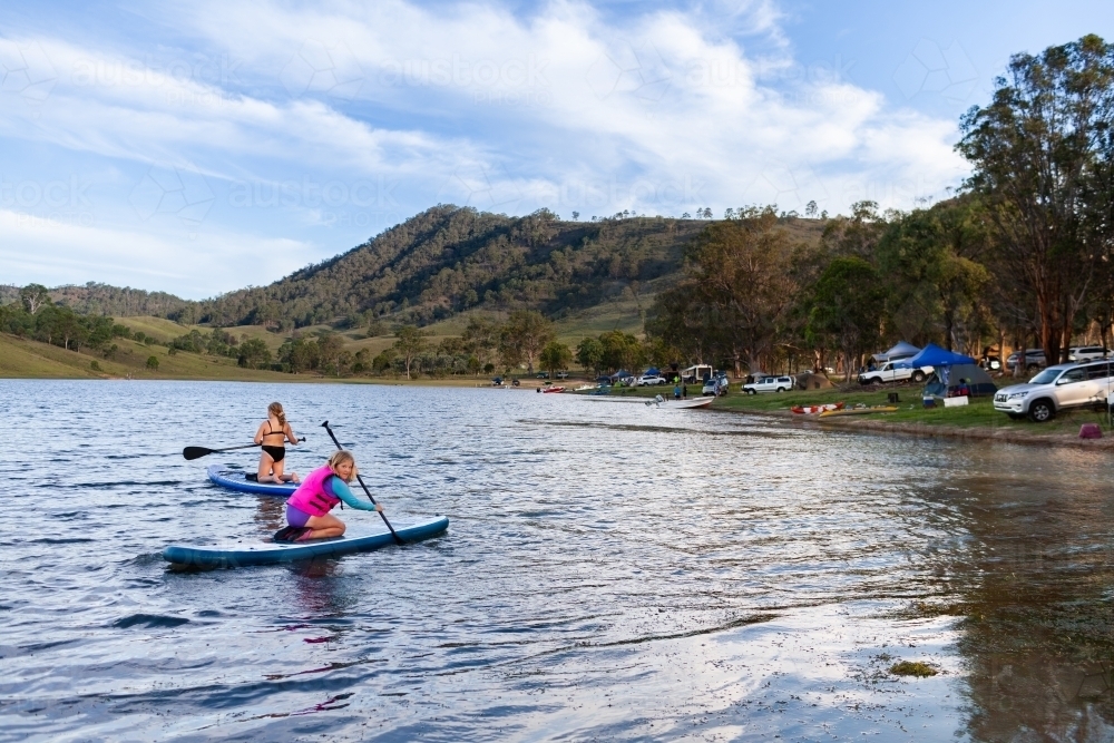 Two Aussie kids out on paddle board on Lake St Clair in summer  - Australian Stock Image