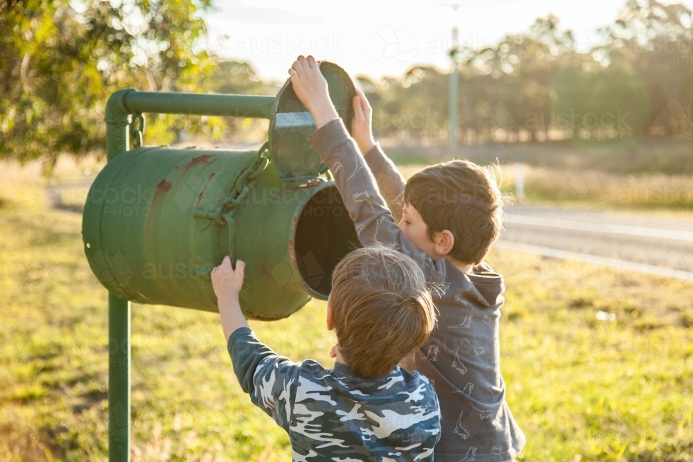 Two boys checking the mailbox for mail in the golden afternoon light - Australian Stock Image