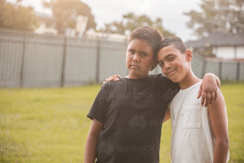 Two boys with their arms around each other looking at the camera - Australian Stock Image