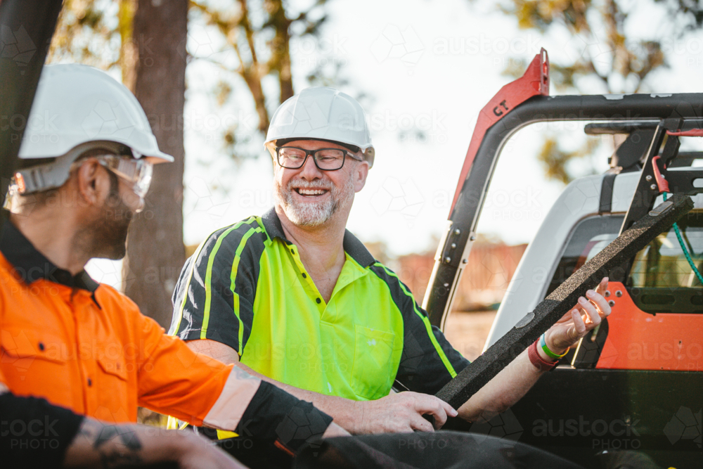 Two builders standing next to ute workmates smiling together - Australian Stock Image