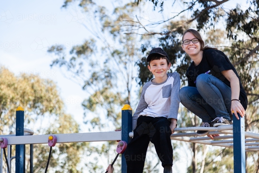 Two children at a park sitting on monkey bars play equipment - Australian Stock Image