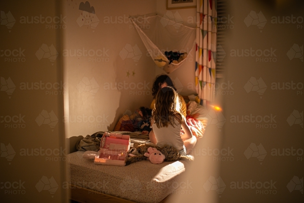 Two children in a bedroom at night playing by the lamplight - Australian Stock Image