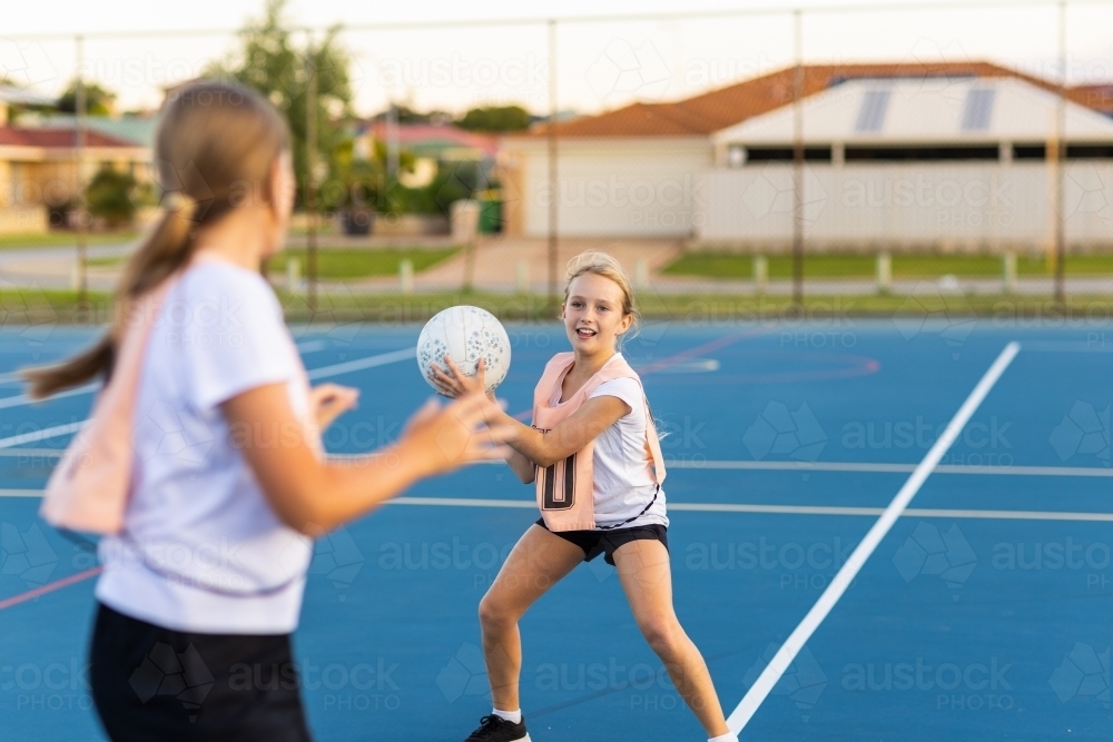 two children playing netball on outside netball court - Australian Stock Image