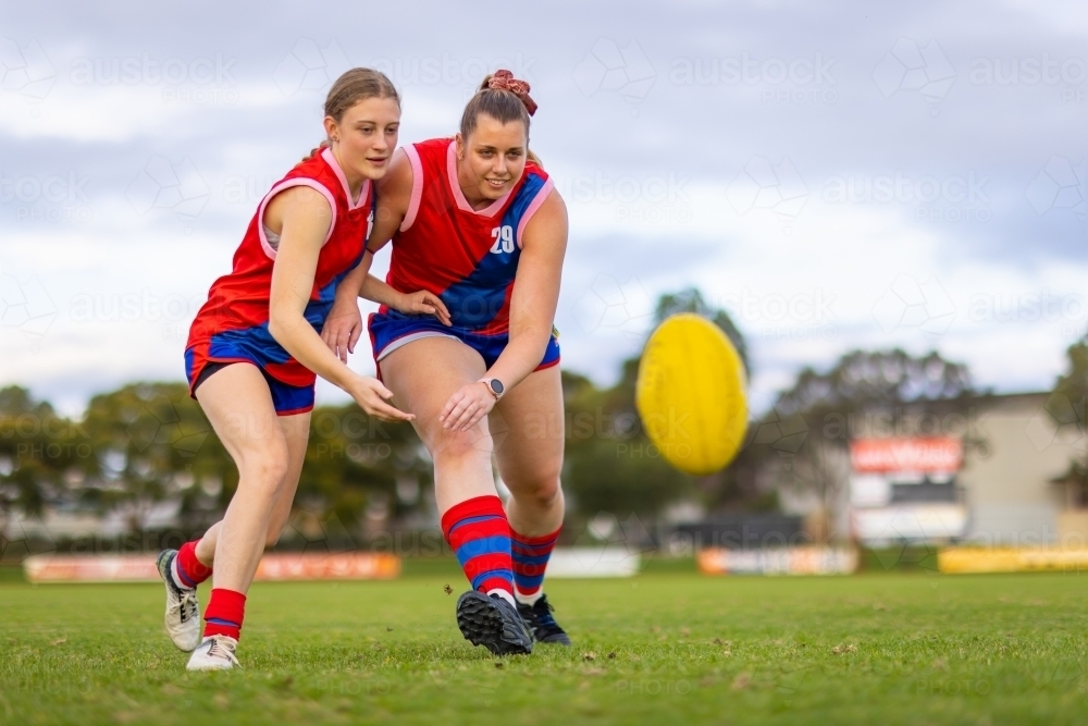 two female football players with their eye on the ball at training - Australian Stock Image