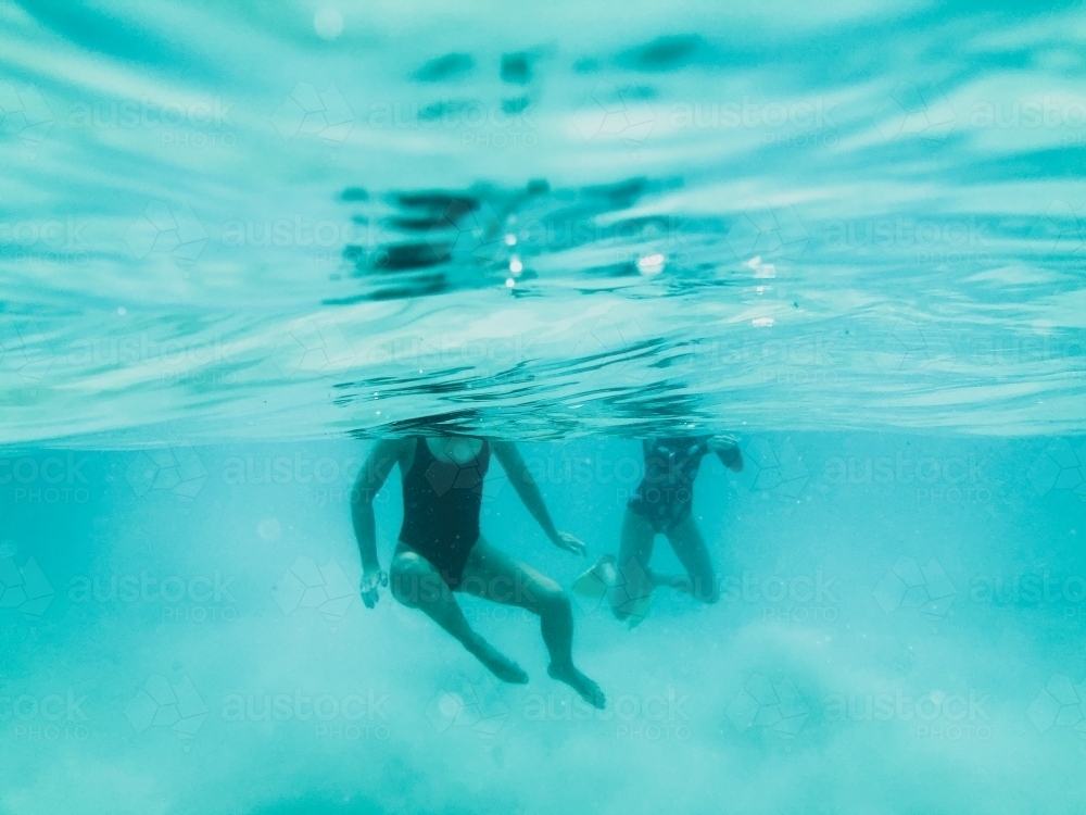 Two females diving underwater swimming towards camera in ocean - Australian Stock Image