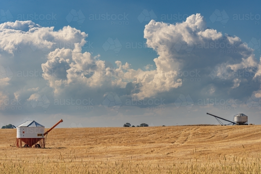 Two field bins sitting in a paddock under a dark cloudy sky - Australian Stock Image