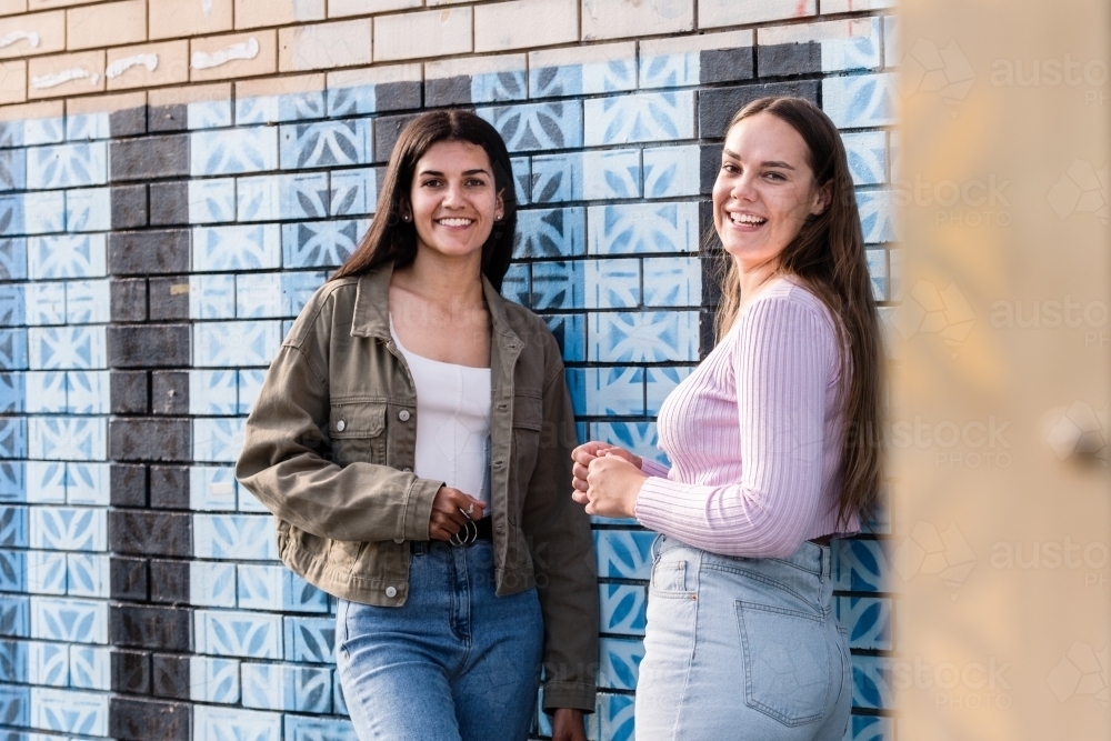 two friends hanging out in an urban setting smilling - Australian Stock Image