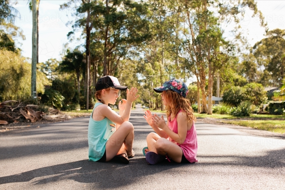 Two girls playing a clapping game on a road - Australian Stock Image