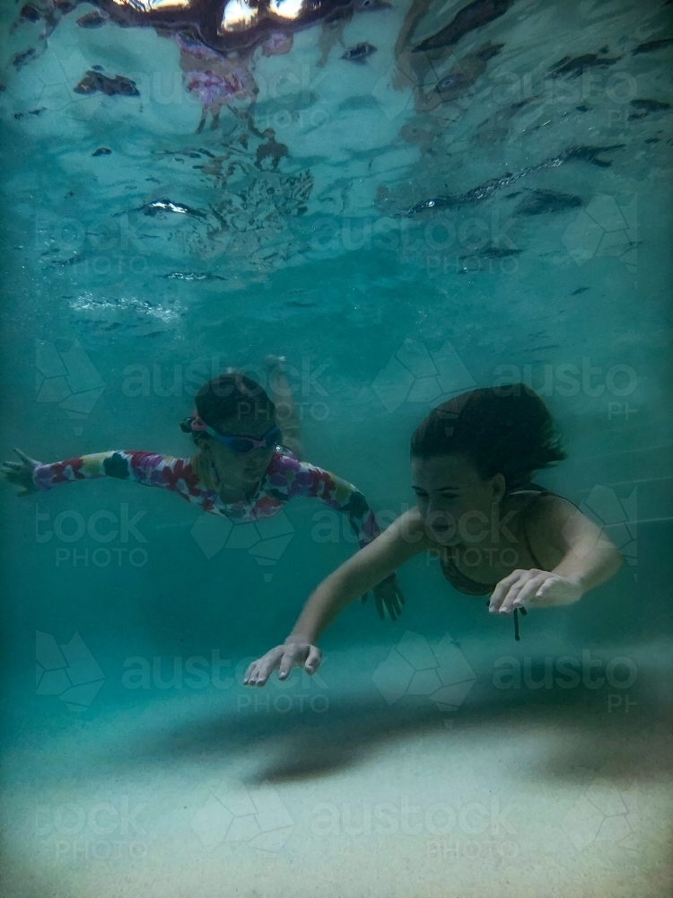 Image Of Two Girls Swimming Towards Camera Underwater In A Pool Austockphoto