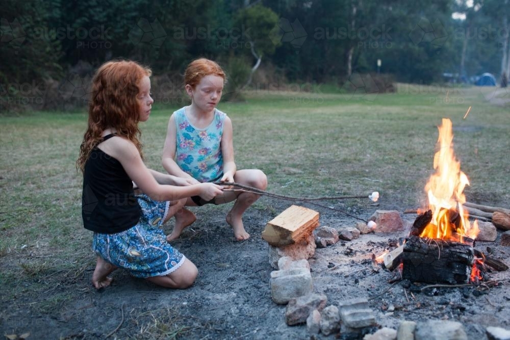 Two girls toasting marshmallows on a campfire - Australian Stock Image