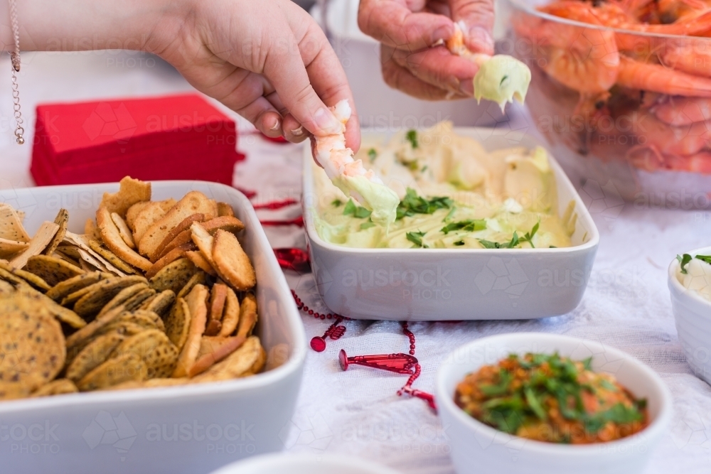 two hands dipping prawns into an avocado mayonnaise - Australian Stock Image