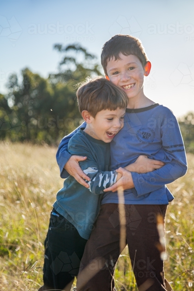 Two happy boys being kids together outdoors - Australian Stock Image