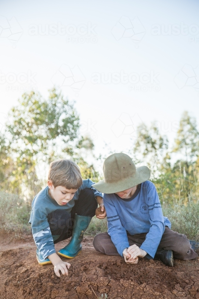 Two happy boys playing in the dirt outside - Australian Stock Image