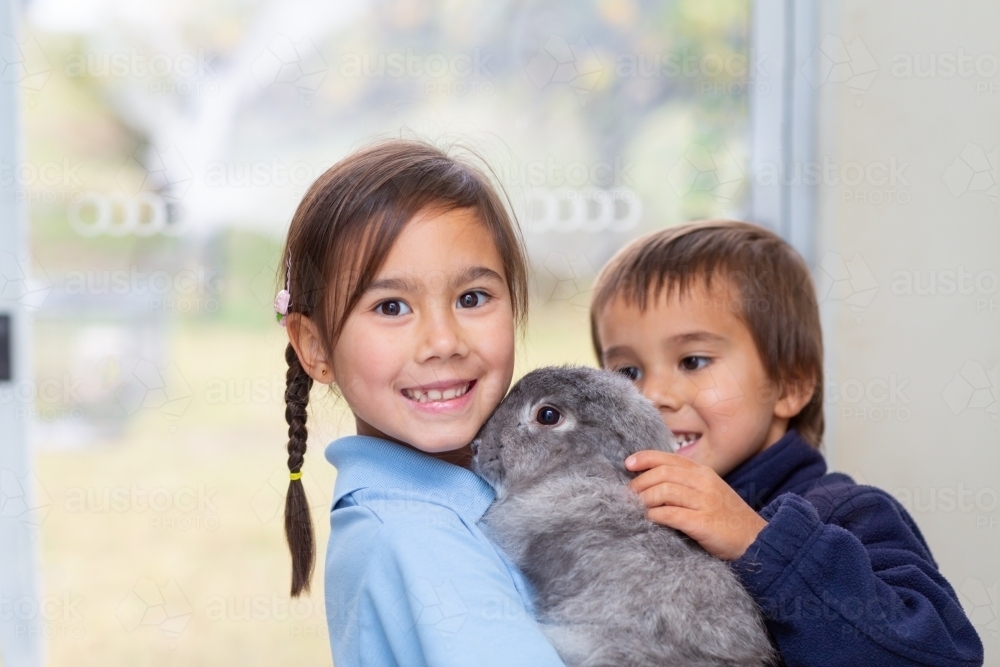 Two happy children with their pet bunny - Australian Stock Image