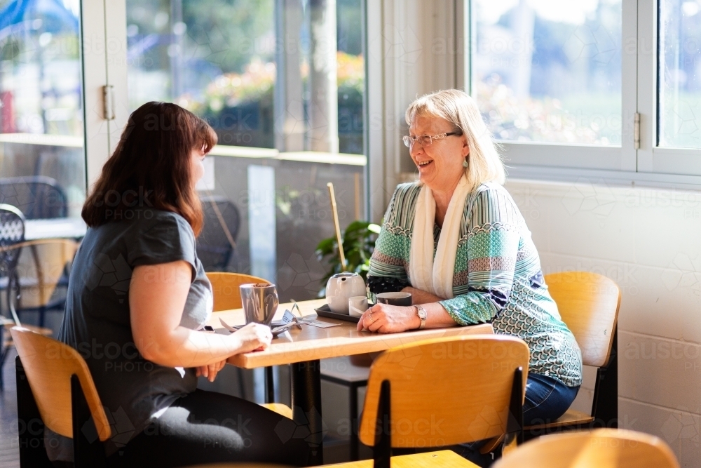 Two happy ladies catching up over coffee at a local cafe - Australian Stock Image