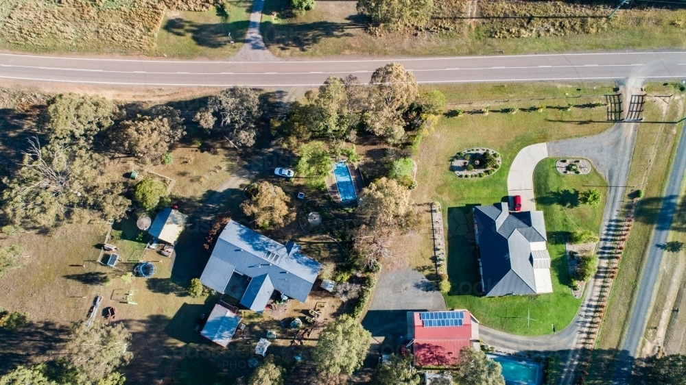 Two houses on the outskirts of a town one neat and tidy the other messy and a paddock - Australian Stock Image