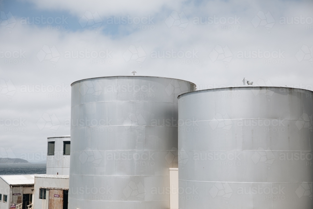 Two large, cylindrical storage tanks with a flat top. - Australian Stock Image