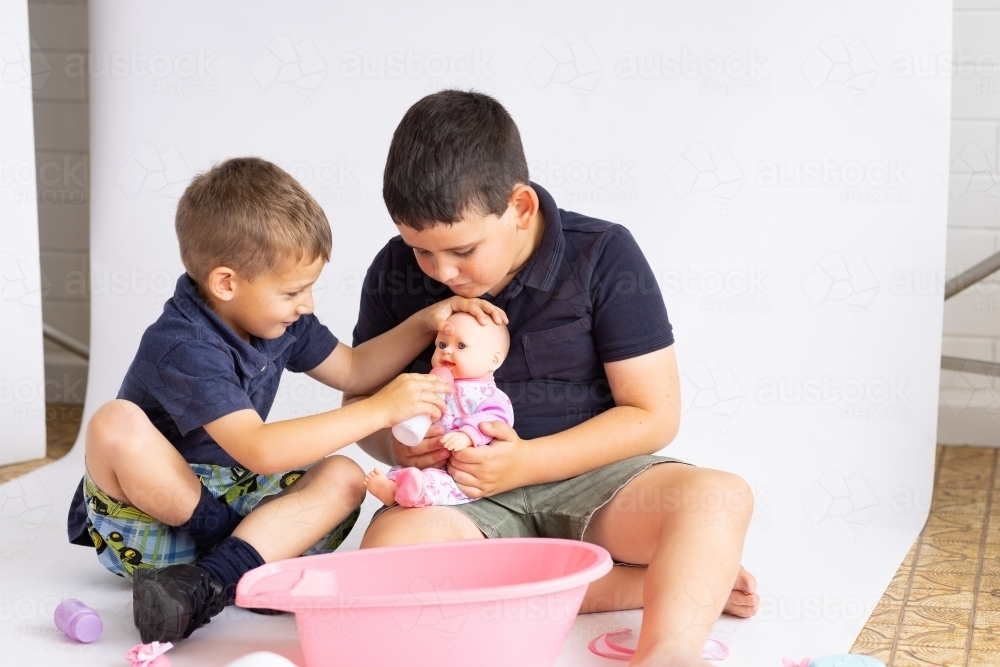 Two little boys playing with a baby doll - Australian Stock Image