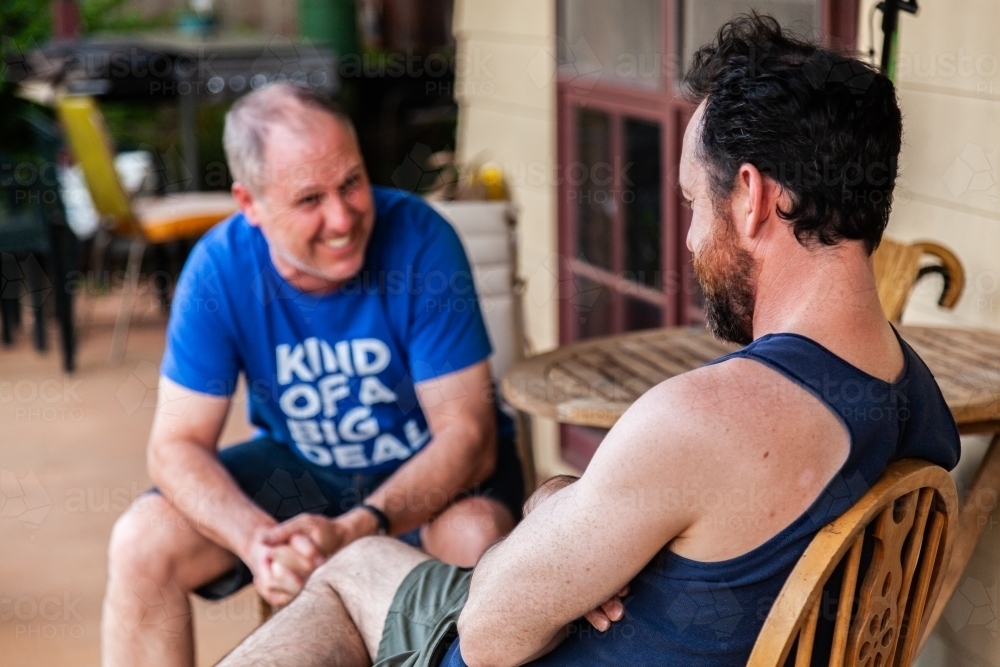 Two men chatting together on verandah - Australian Stock Image