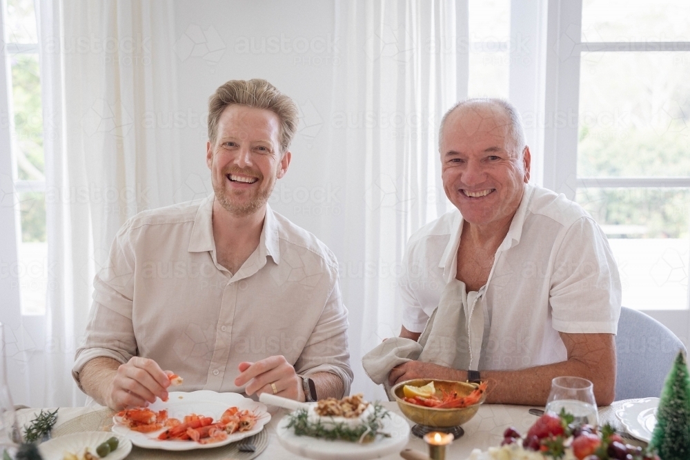 Two men deveining prawns at dinner table - Australian Stock Image