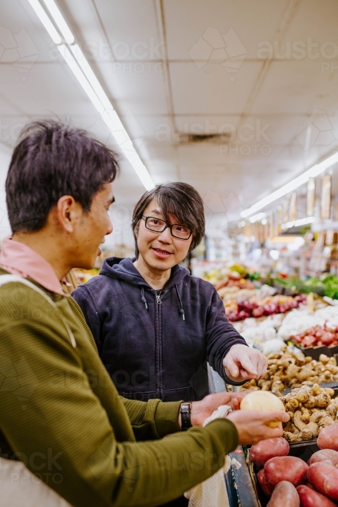 Two men having a conversation in fresh food supermarket - Australian Stock Image