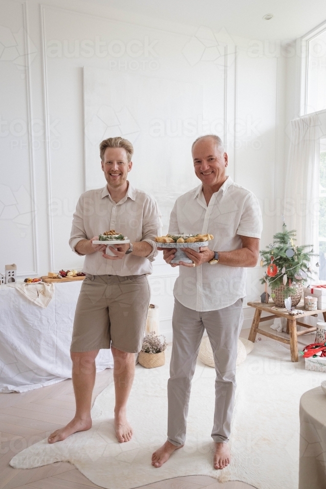 Two men holdig platters of Christmas food - Australian Stock Image