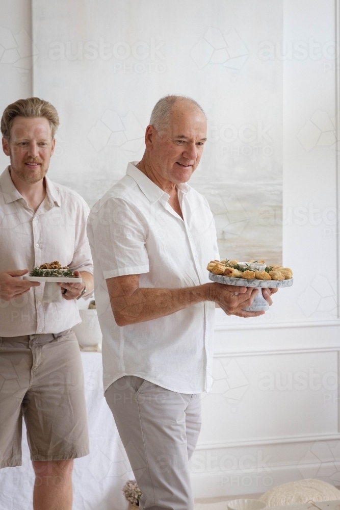 Two men holdig platters of Christmas food - Australian Stock Image