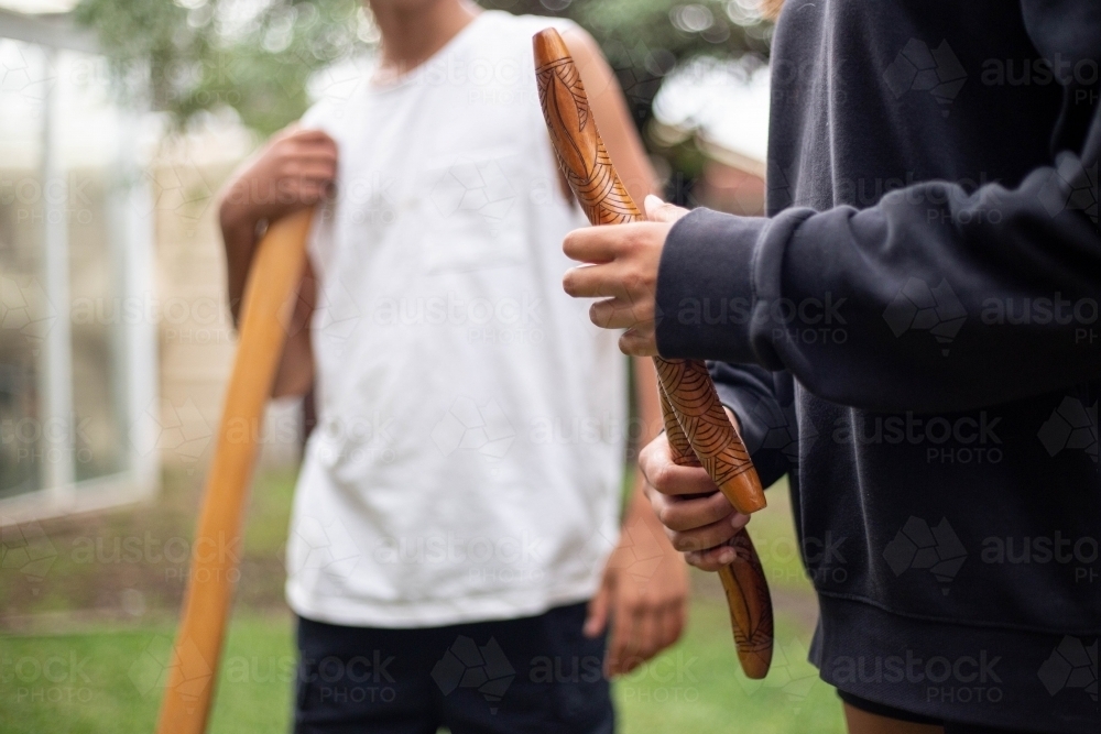 Two people holding Aboriginal instruments in backyard - Australian Stock Image