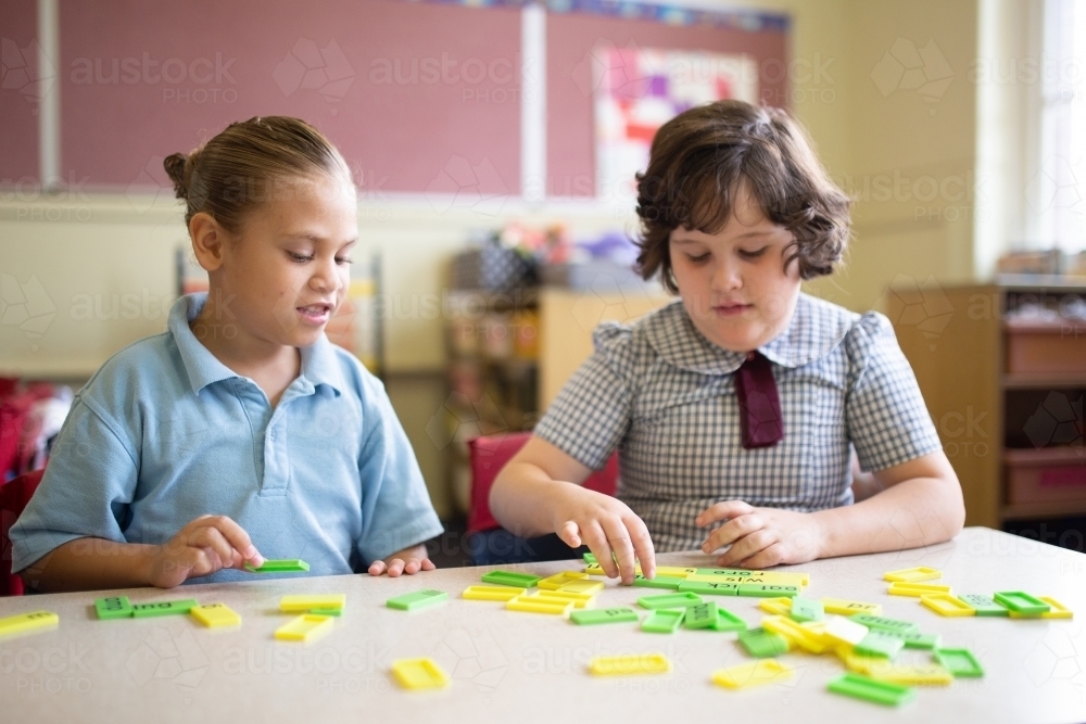 Two primary school girl students collaborating with coloured word tiles - Australian Stock Image