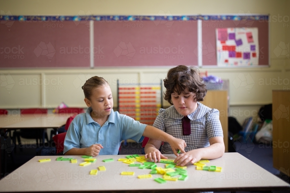 Two primary school girl students collaborating with coloured word tiles - Australian Stock Image