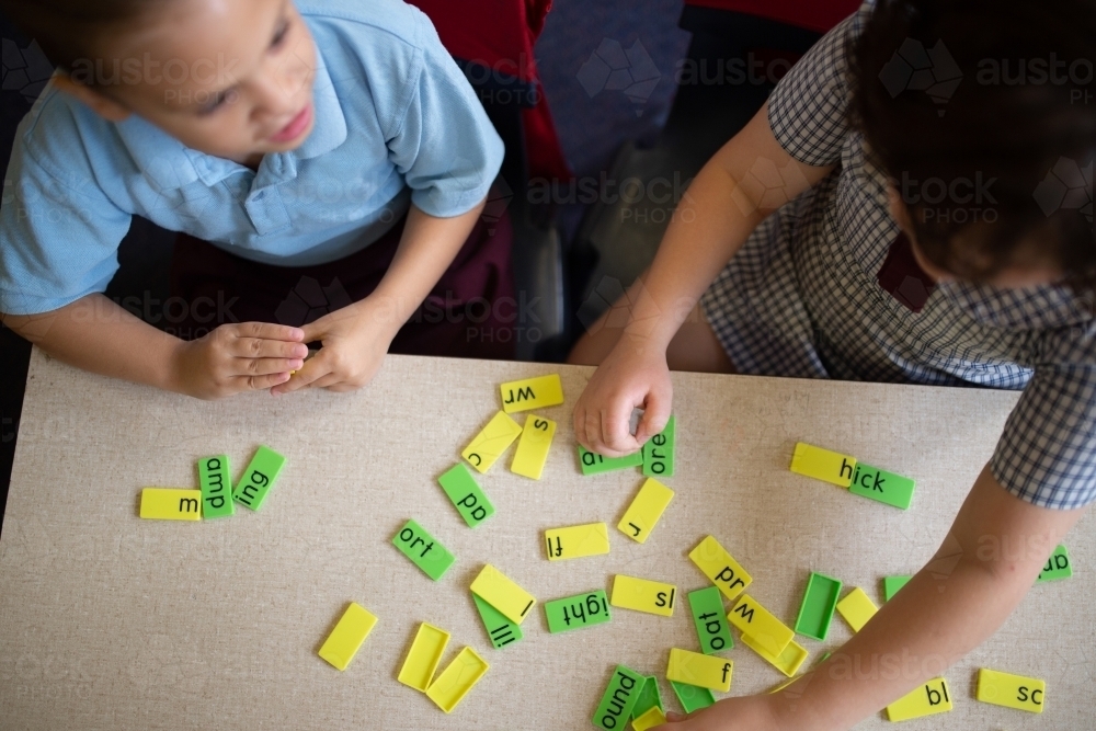 Two primary school girl students collaborating with coloured word tiles - Australian Stock Image