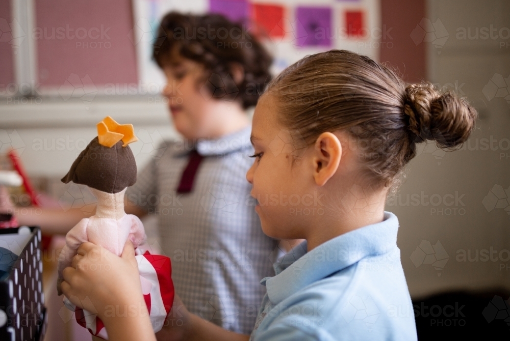 Two primary school girl students playing with a hand-made doll - Australian Stock Image