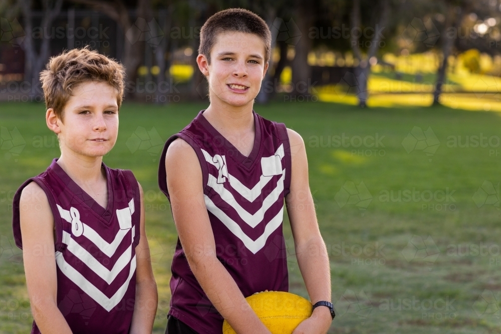 two schoolboys in football uniform standing outdoors - Australian Stock Image