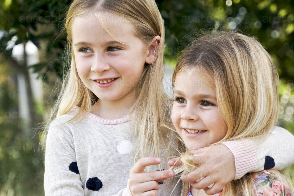 Two sisters holding each other looking away - Australian Stock Image